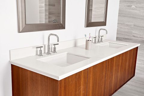 Double bathroom vanity with wood base and white porcelain countertops. Silver faucets.