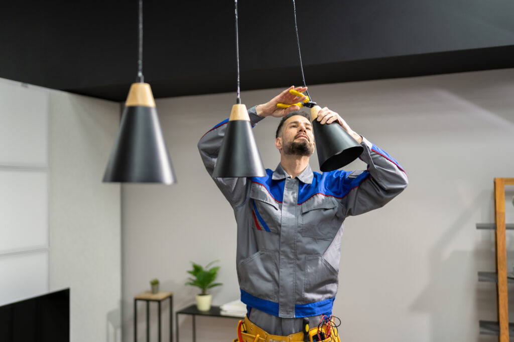 Professional electrical technician installing pendant lights over kitchen island.