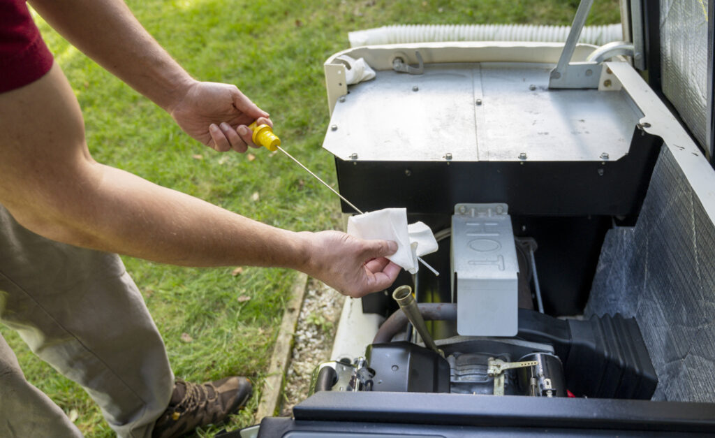 Technician checking engine oil in generator, cleaning oil dipstick, measuring oil level