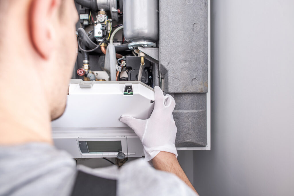 Close-up of technician fixing a central heating furnace system.