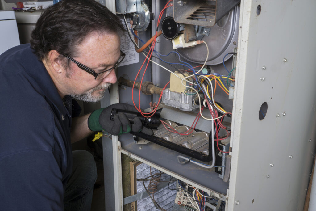 Male technician repairing a furnace.