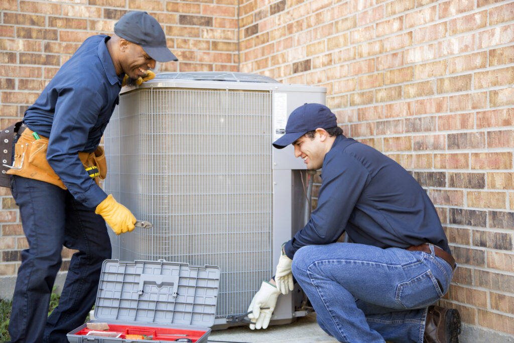 team of air conditioner repairmen at work as they prepare to begin work by gathering appropriate tools from their tool box